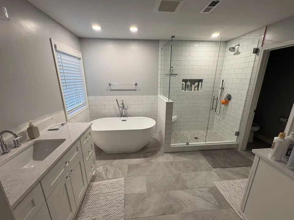Bathroom remodeling from Queen City Renovation in Mint Hill, NC: primary bathroom with a freestanding tub, glass-enclosed white subway tile shower and gray tile floor