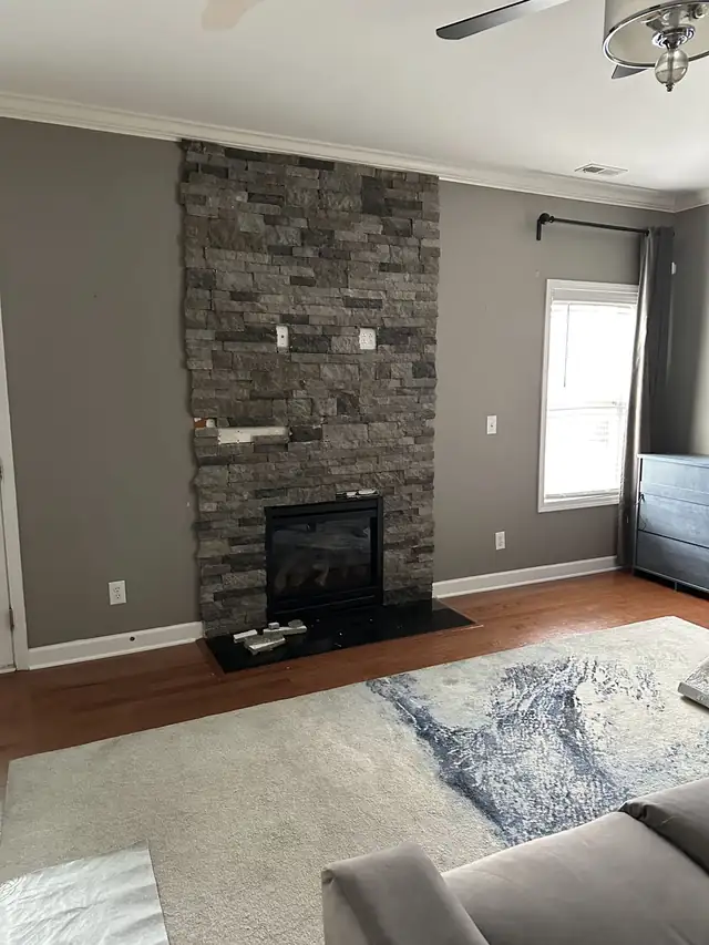 Living room fireplace refaced floor to ceiling in gray stacked stone with a dark hearth