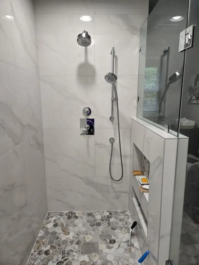 Large-format white marble-look porcelain shower with handheld shower and recessed niche